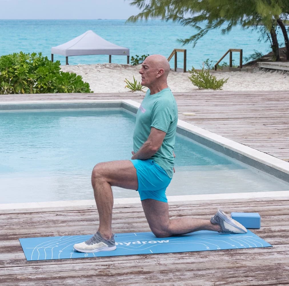 Hydrow member stretching on a Hydrow mat beside a pool